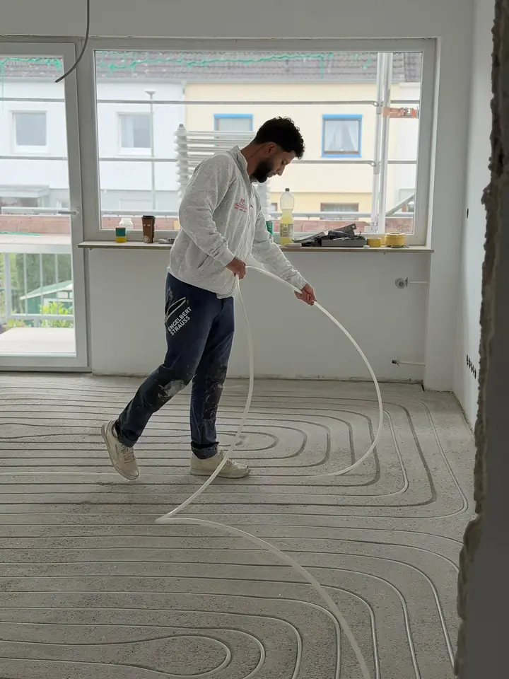 Monteur verlegt Heizrohre in die gefrästen Kanäle